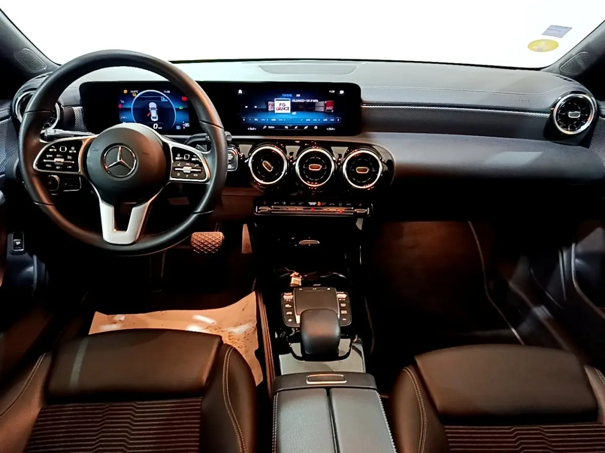 Vue intérieure avant de la Mercedes CLA 180 d Business Line 2021, tableau de bord noir avec écran tactile et volant multifonctions.