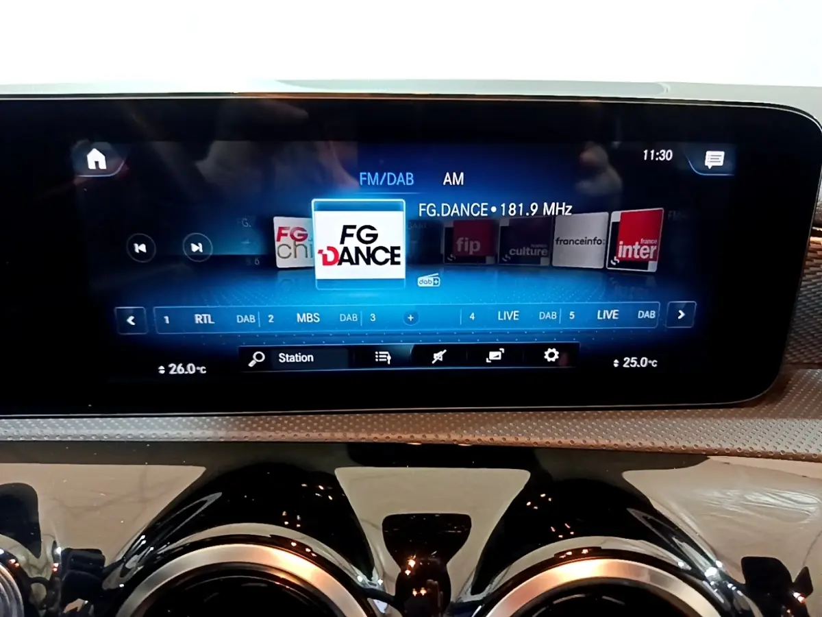 Écran tactile central affichant la radio FM/DAB dans l’habitacle d’une Mercedes CLA 180 d gris clair.