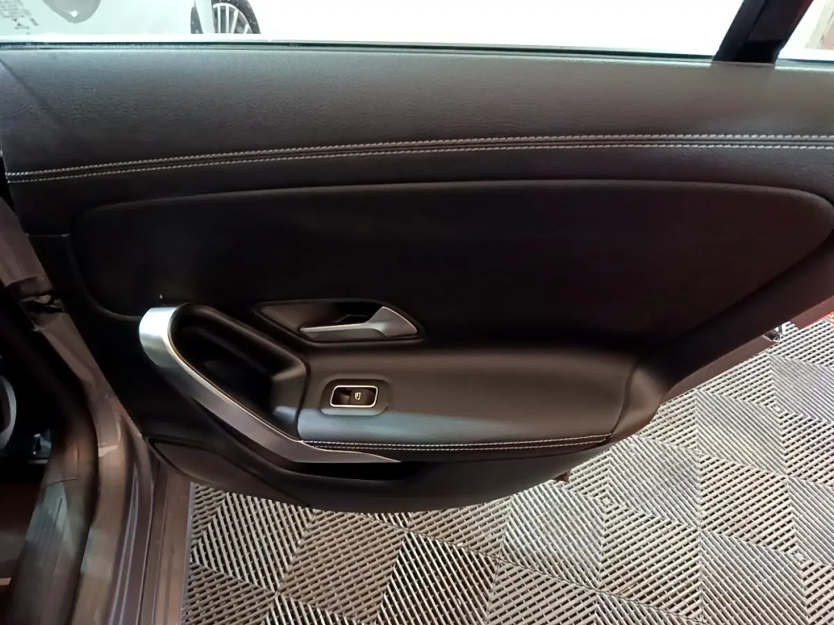 Vue intérieure de la porte côté gauche en cuir noir avec surpiqûres blanches d'une Mercedes CLA 180 d Business Line 2021.