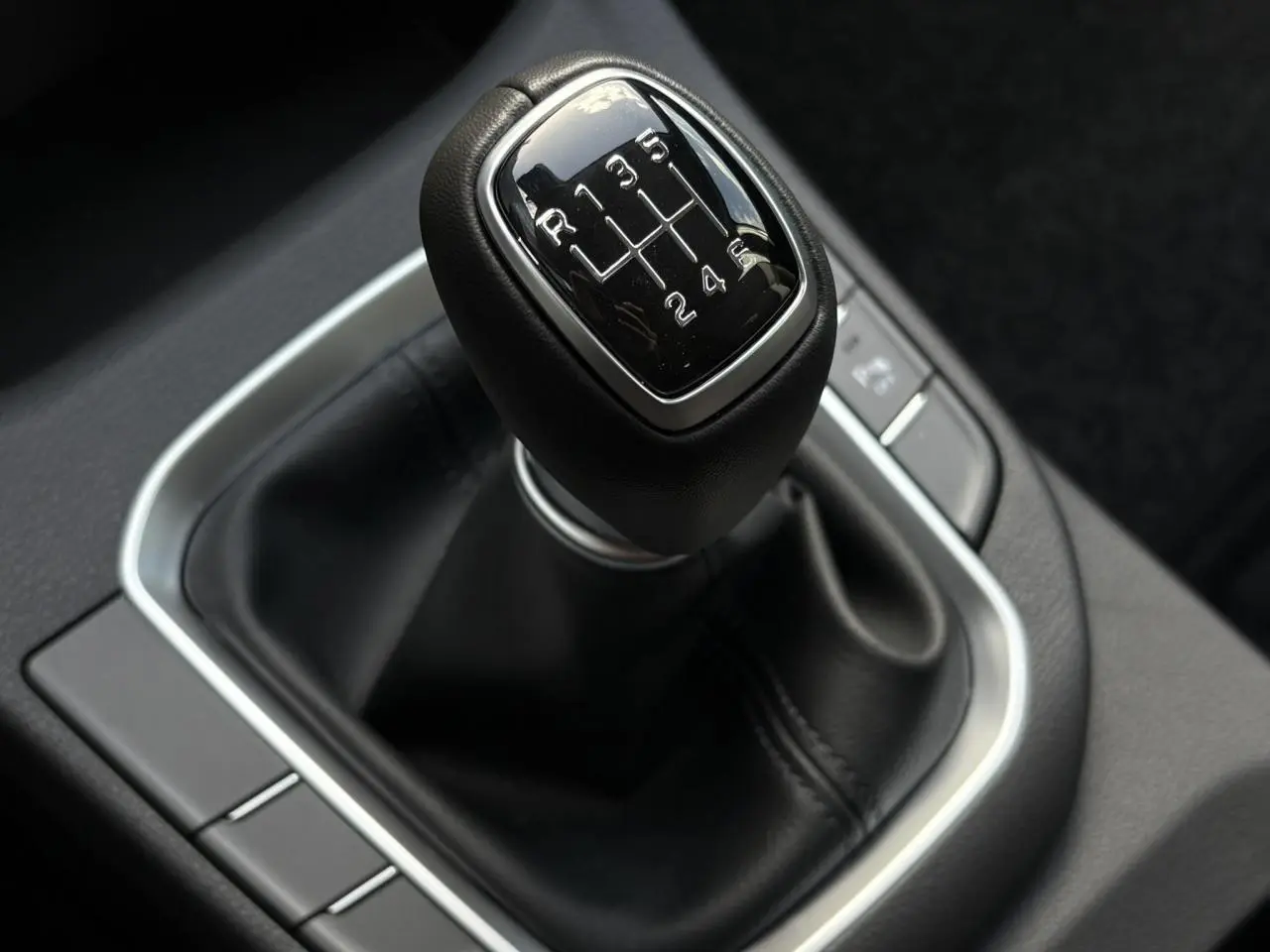 Gros plan sur le levier de vitesses manuel cuir noir de la Hyundai i30 SW T-GDI 120 Modern, intérieur sombre.