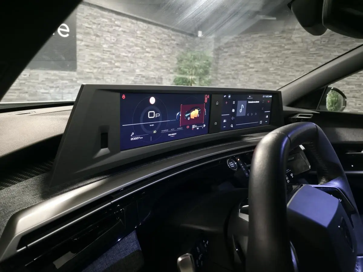 Vue intérieure du tableau de bord du Peugeot 5008 blanc 2025, avec double écran HD panoramique et volant compact cuir noir.