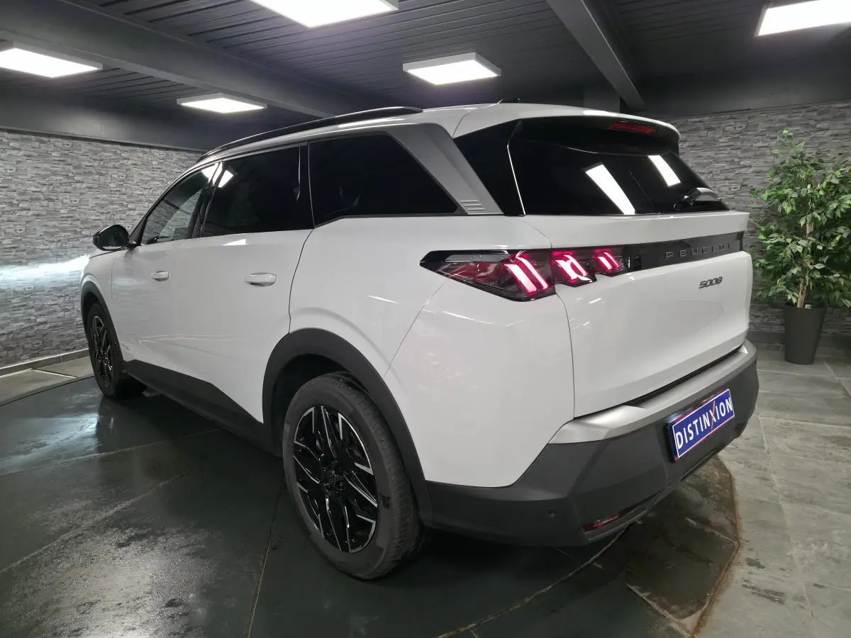 Peugeot 5008 blanc en 3/4 arrière droit, feux arrière LED 3 griffes et jantes alliage noires brillantes.