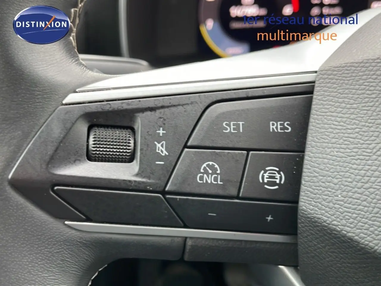 Gros plan sur les commandes du volant d'une SEAT LEON 2025 gris magnétique, boutons de régulateur de vitesse et volume.