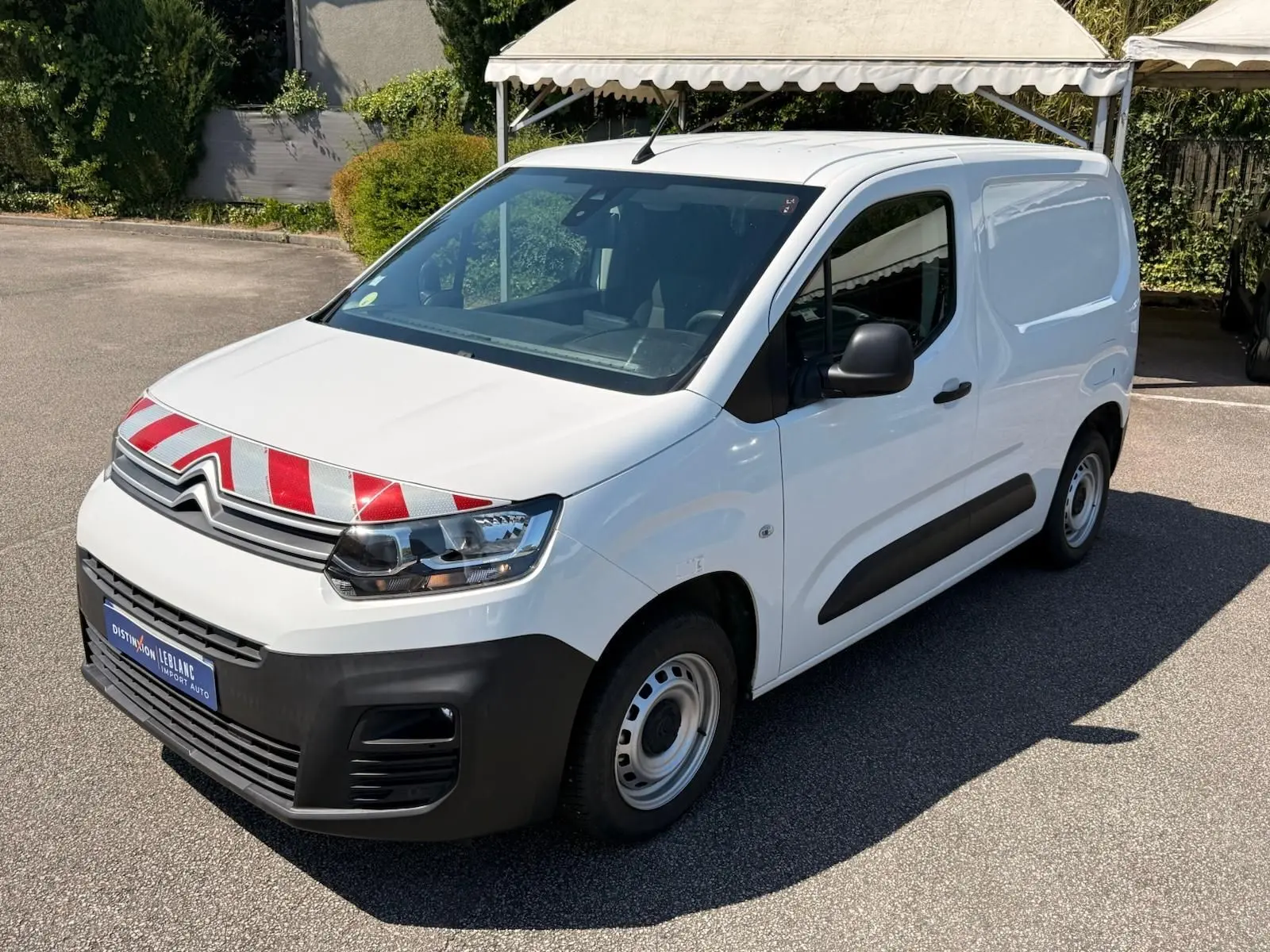 Vue 3/4 avant droit d’un Citroën Berlingo Van blanc 2020 avec marquage rouge et blanc sur le capot et protections noires.