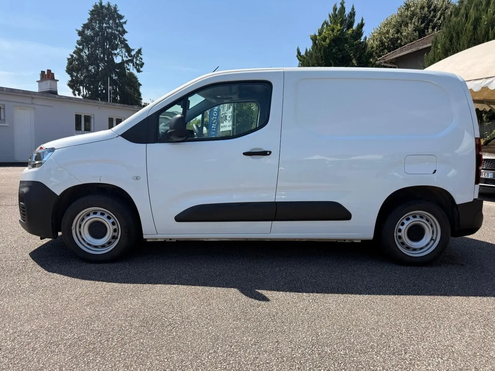 Vue de profil côté gauche d’un utilitaire Citroën Berlingo Van blanc avec porte latérale et jantes acier simples.