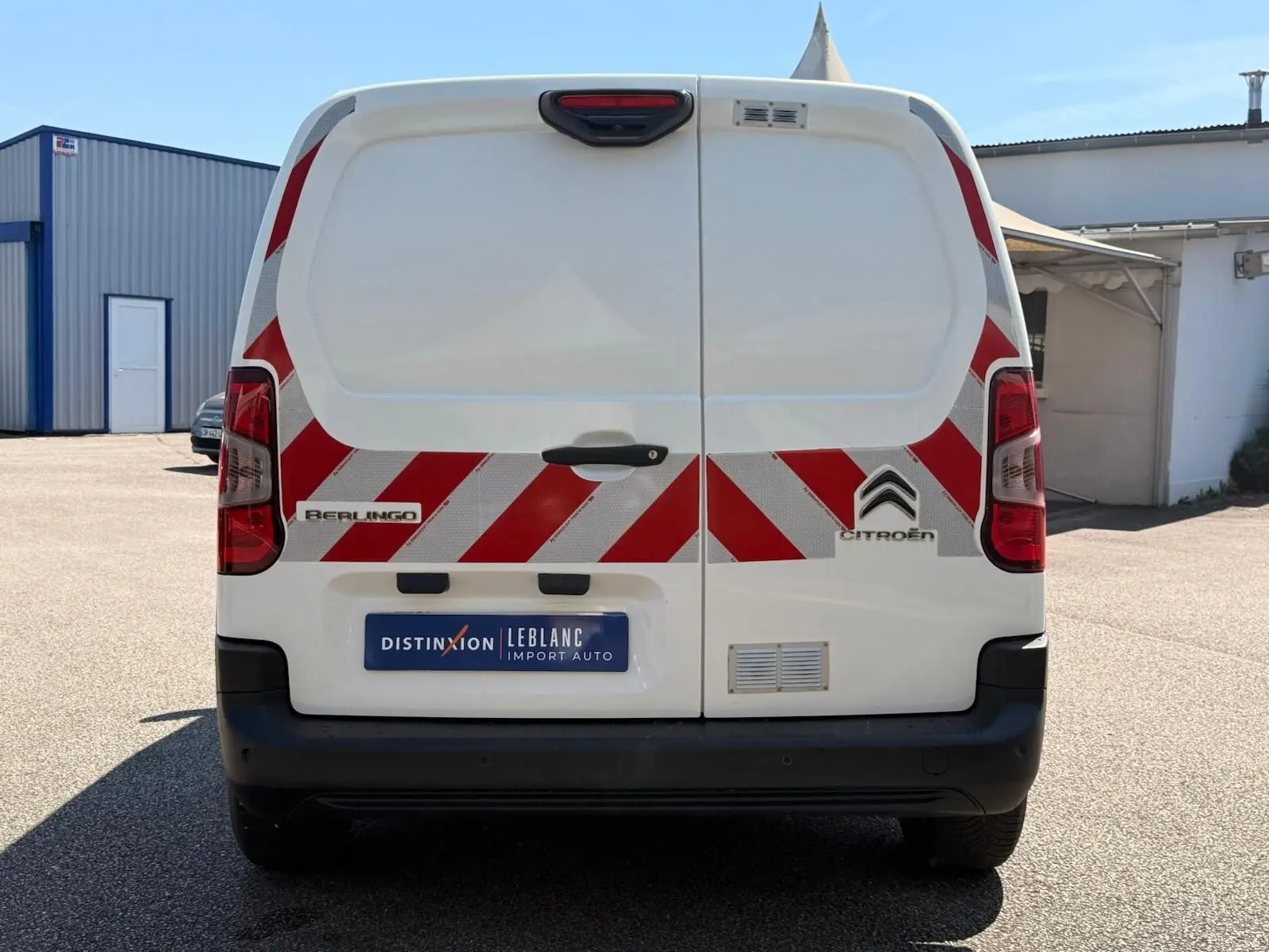 Vue arrière d’un utilitaire blanc Citroën Berlingo Van 2020 avec bandes réfléchissantes rouges et blanches.