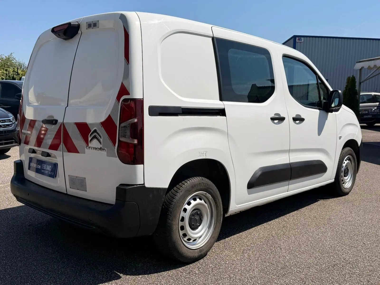 Vue 3/4 arrière droite d'un Citroën Berlingo Van blanc 2020 avec bandes rouges réfléchissantes sur les portes arrière.