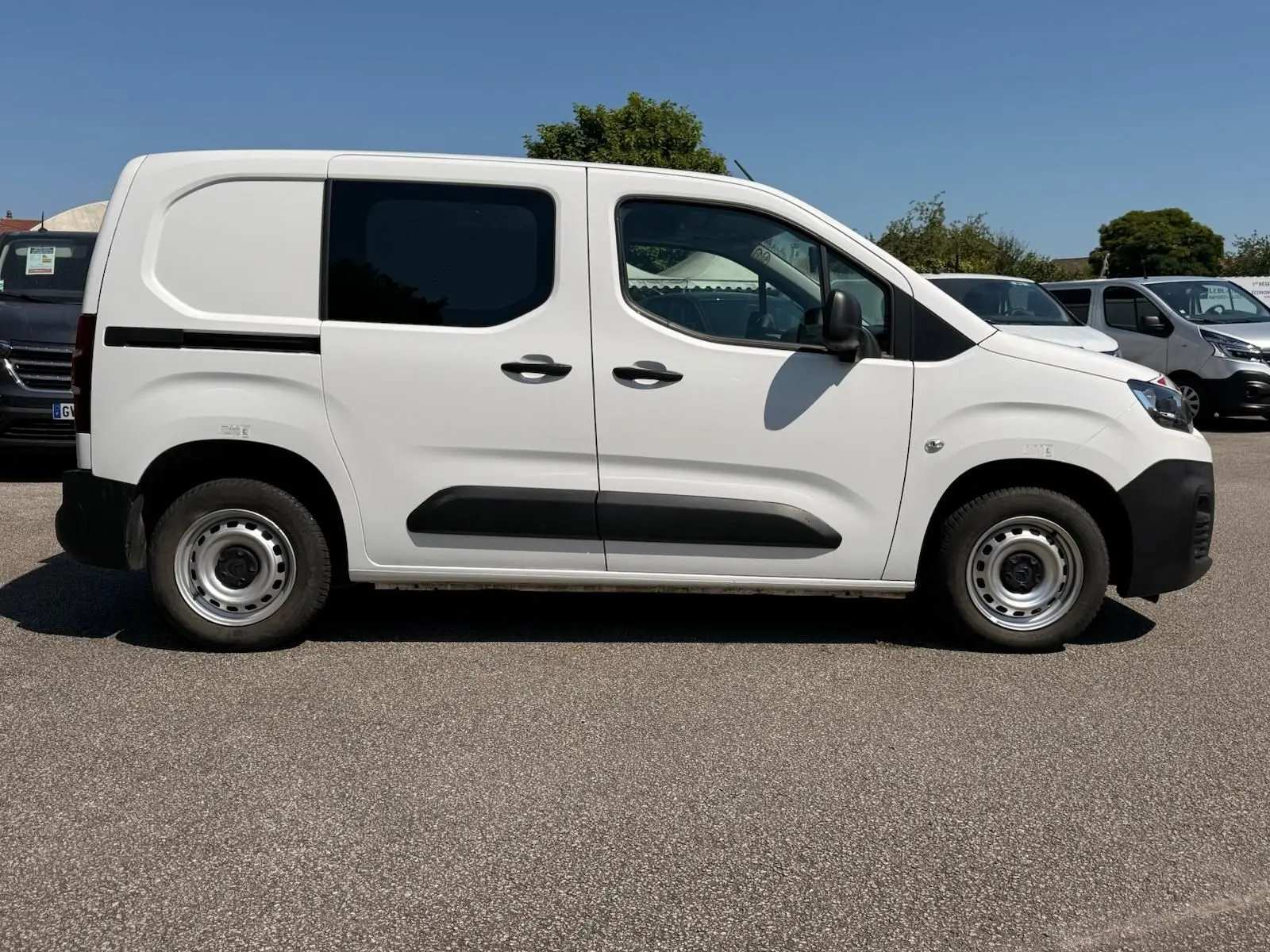 Vue de profil côté droit d'un utilitaire Citroën Berlingo Van blanc avec porte latérale coulissante et jantes acier.