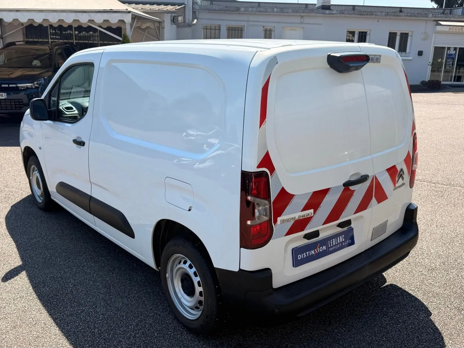 Vue 3/4 arrière droite d'un Citroën Berlingo Van blanc 2020 avec bandes réfléchissantes rouges sur les portes arrière.