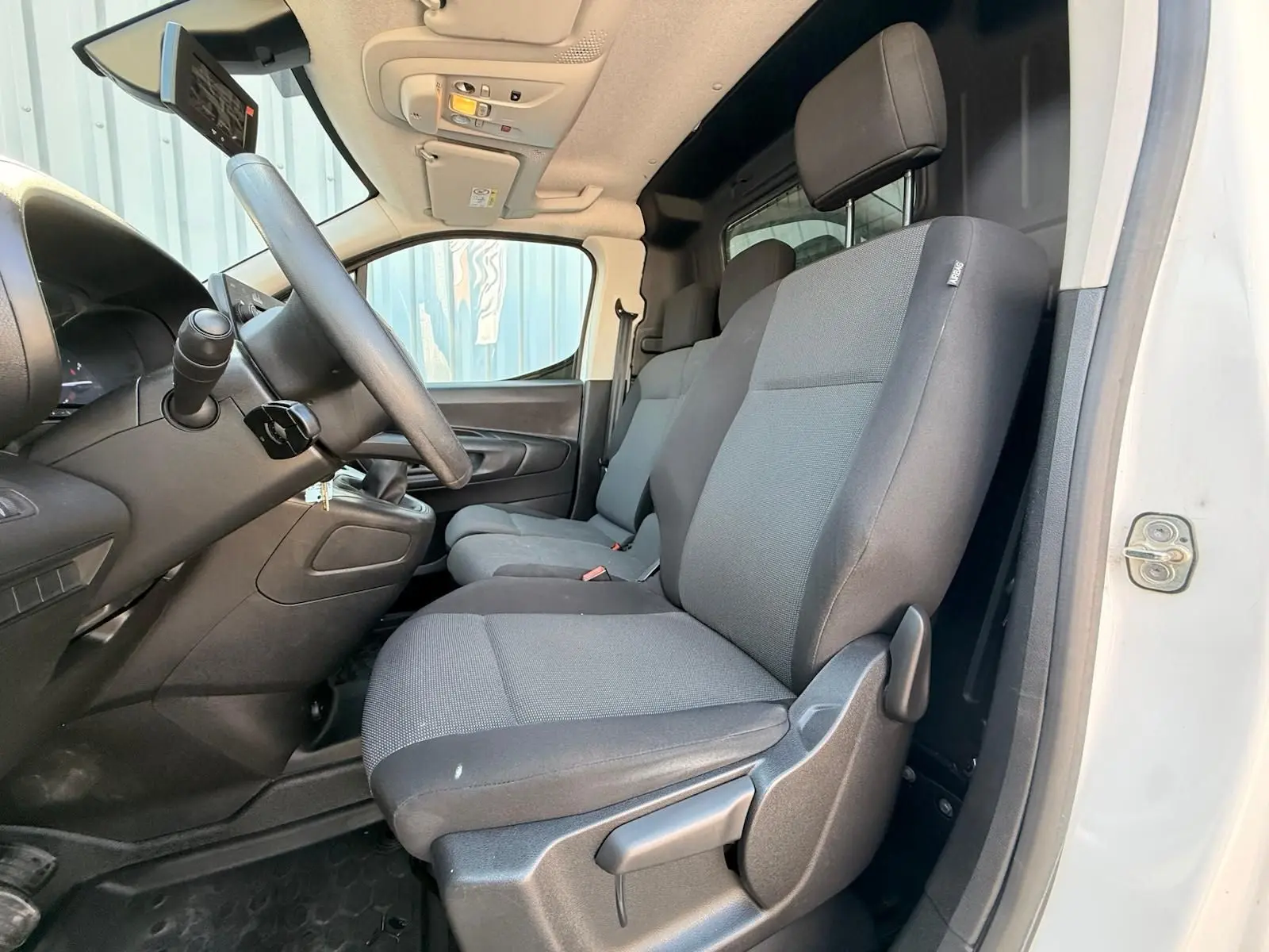 Vue intérieure côté conducteur du Citroën Berlingo Van blanc 2020, sièges tissu gris et tableau de bord noir.