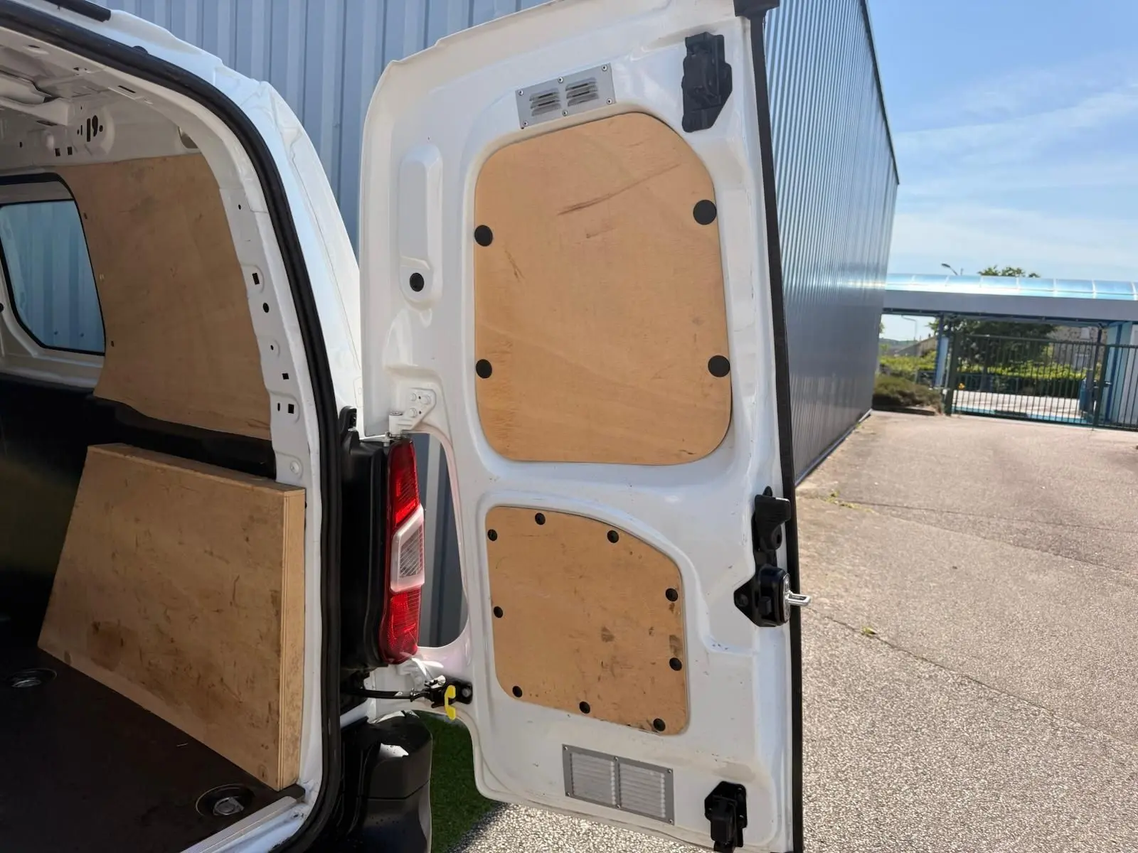 Vue arrière droite ouverte d’un Citroën Berlingo Van blanc 2020 avec aménagement bois intérieur des portes et du coffre.
