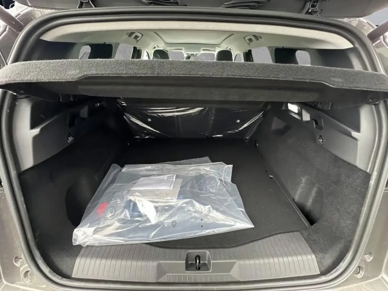 Coffre ouvert d’un Citroën C5 Aircross gris platinium, vue arrière montrant l’espace de chargement vide avec couverture de coffre.