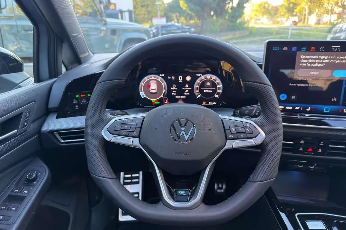 Vue centrée sur le volant cuir multifonctions de la Volkswagen Golf E-TSI 150 R-Line avec tableau de bord numérique.