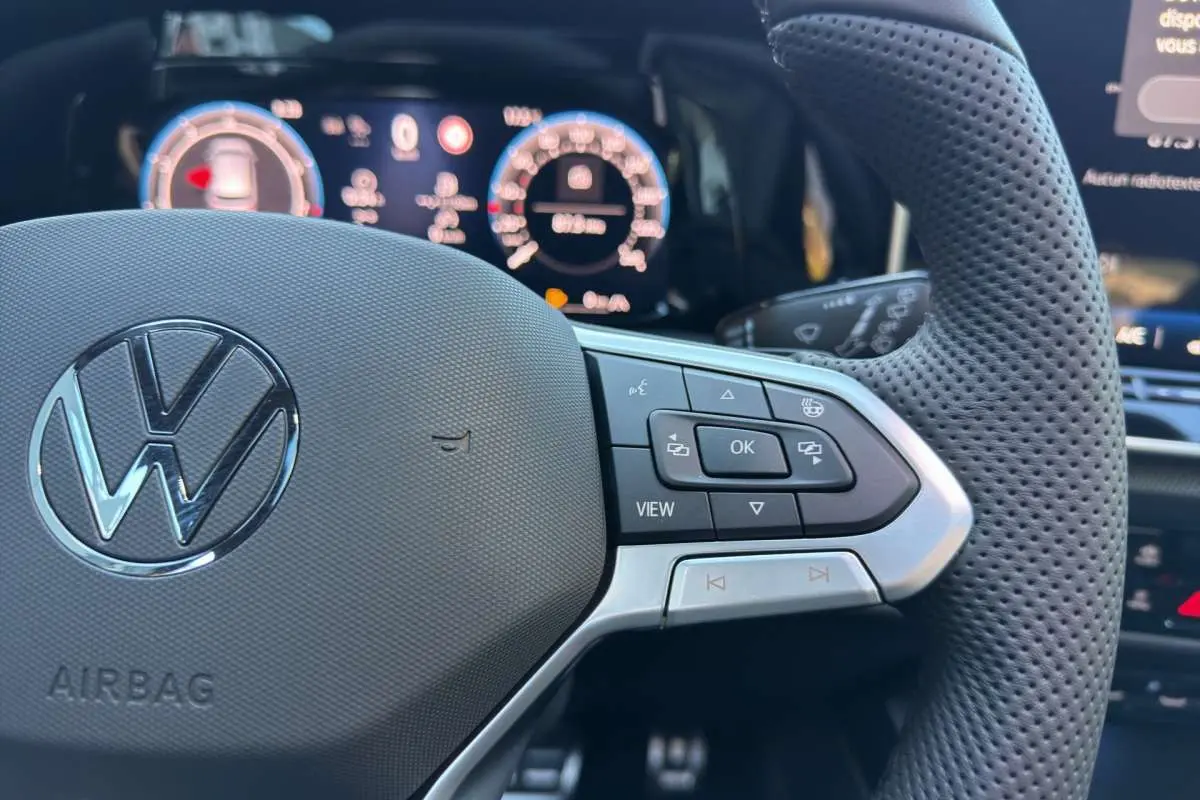 Gros plan sur le volant cuir perforé côté droit de la Volkswagen Golf E-TSI 150 R-Line avec commandes multifonctions.