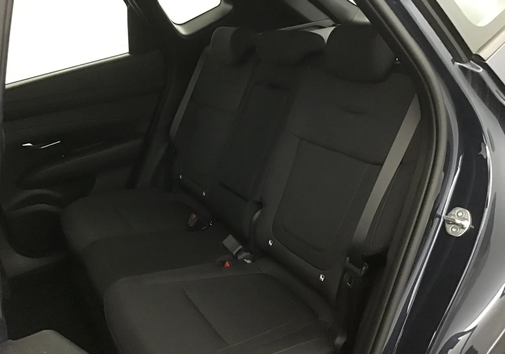 Vue intérieure sur les sièges arrière noirs du Hyundai Tucson 2025 bleu Salling, avec portière droite ouverte.