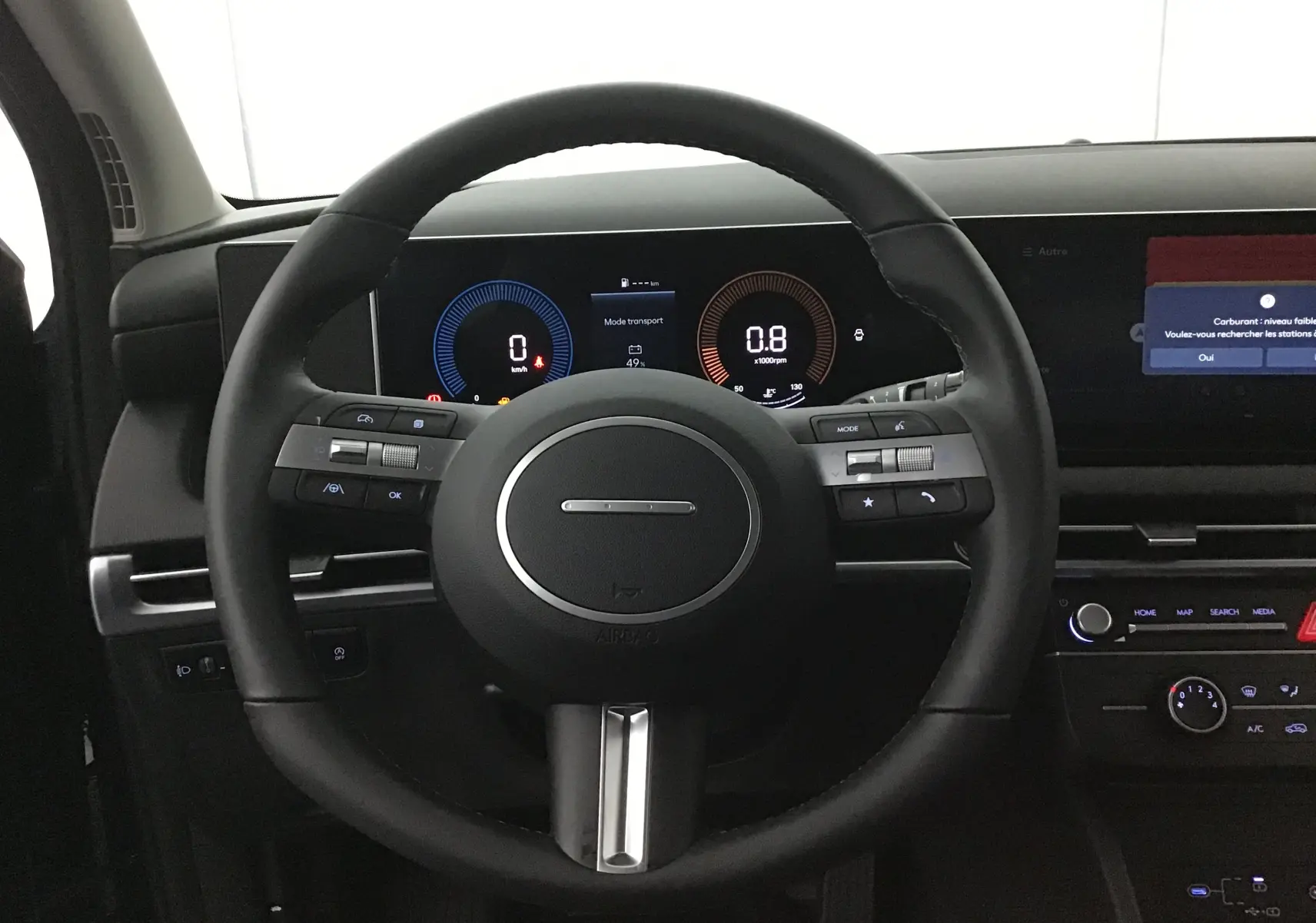 Vue intérieure centrée sur le volant cuir du Hyundai Tucson 2025 avec tableau de bord numérique et écran tactile.