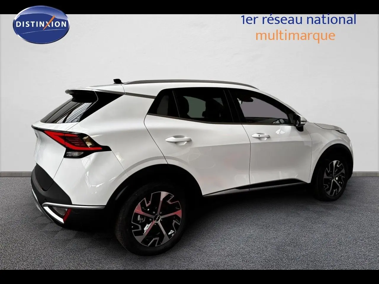 Vue 3/4 arrière droite d’un KIA SPORTAGE blanc nacré métal avec jantes noires et toit noir contrasté.