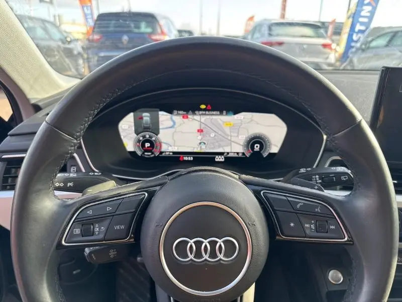 Vue intérieure centrée sur le volant cuir multifonction noir de l'Audi A4 Avant 2022 avec tableau de bord numérique affichant la navigation.