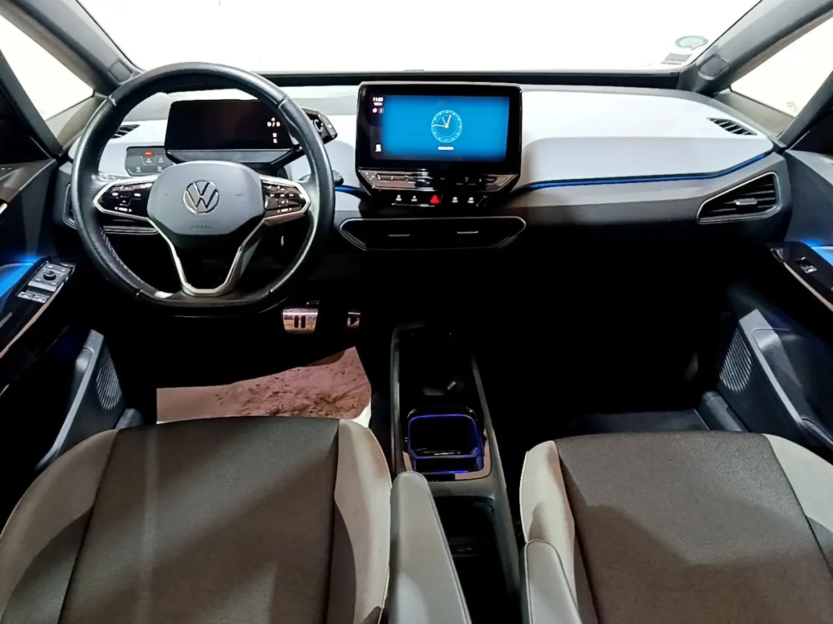 Vue intérieure avant du Volkswagen ID.3 77 kWh Pro S, tableau de bord moderne avec écran tactile central et éclairage d'ambiance bleu.