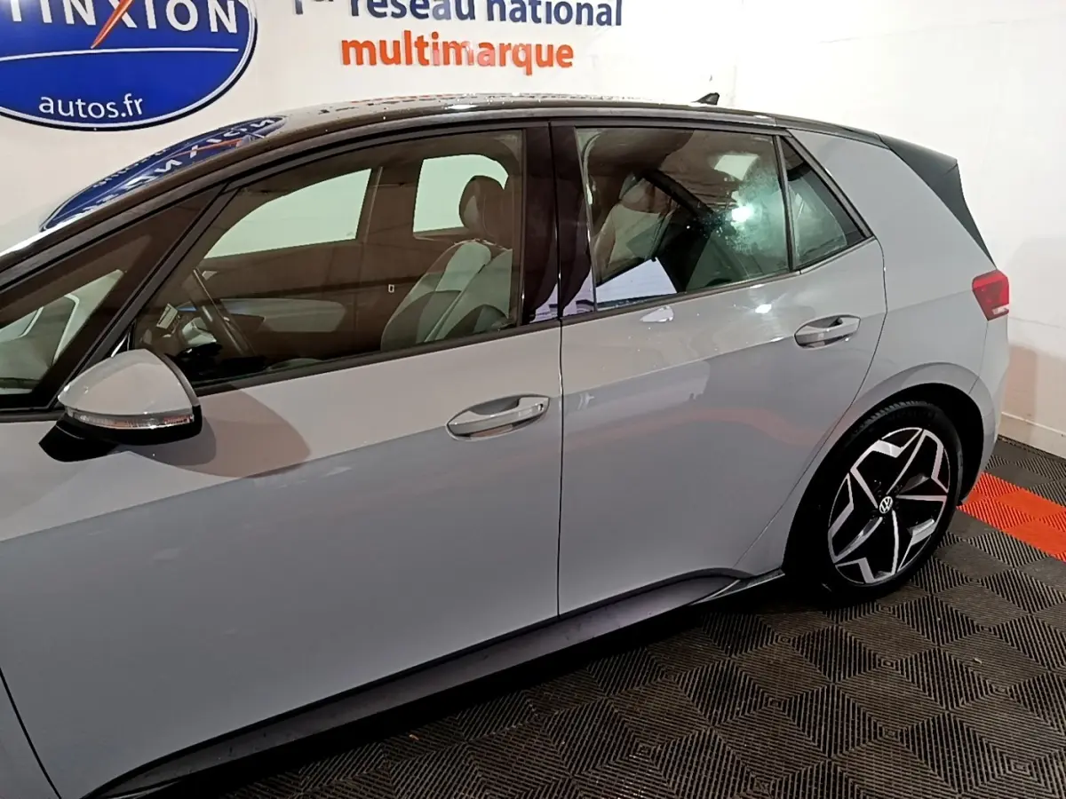 Vue latérale droite d'une Volkswagen ID.3 gris foncé avec jantes noires et toit noir dans un showroom.