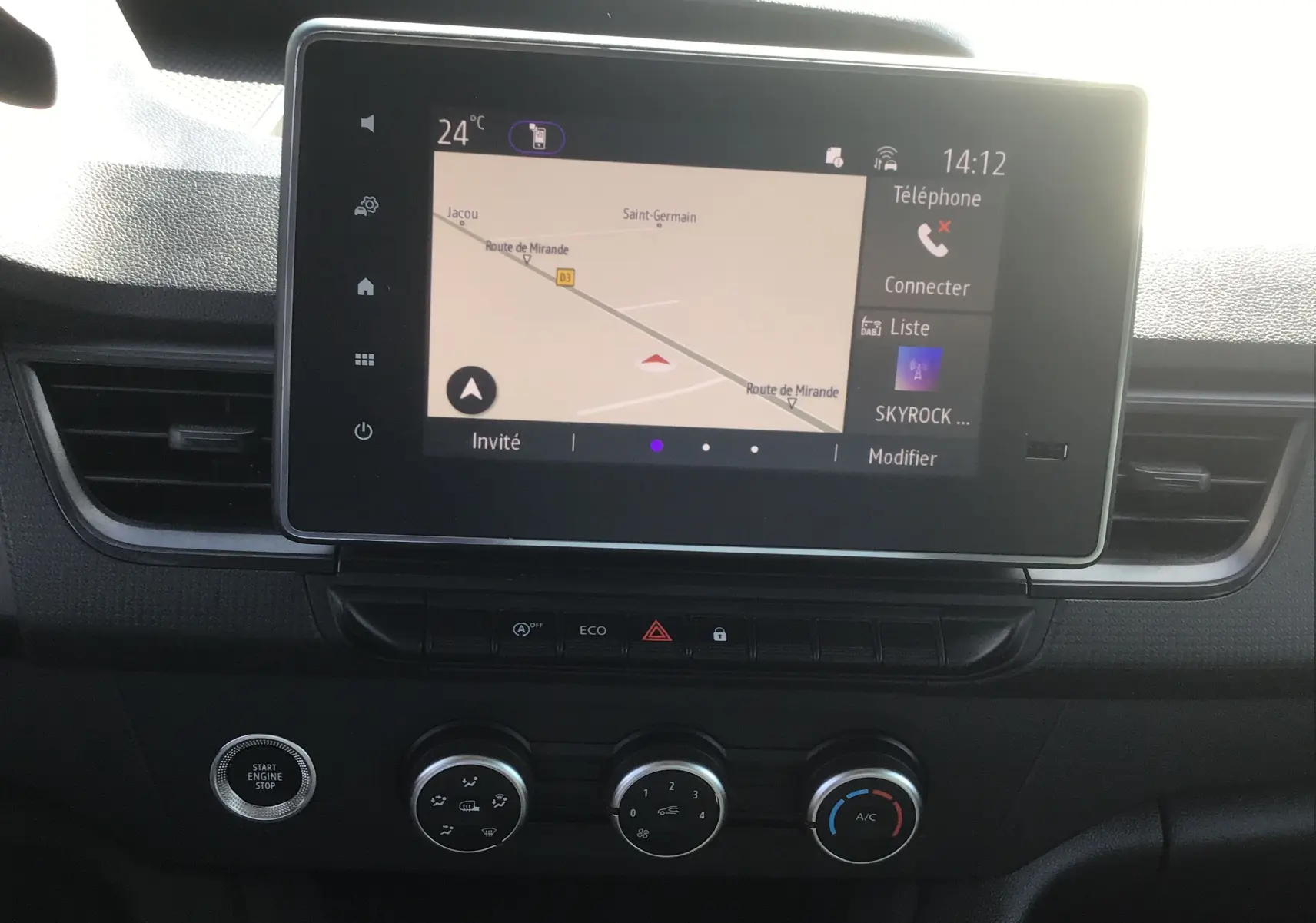 Vue rapprochée de l’écran tactile central du Renault Kangoo 2024 blanc, affichant la navigation et les commandes climatisation.