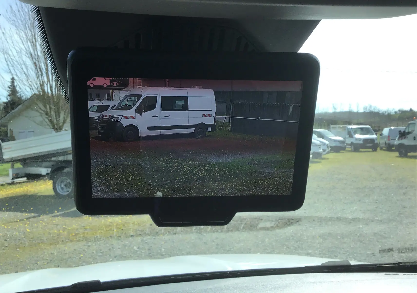 Écran intérieur montrant en vue latérale gauche un Renault Kangoo Van blanc stationné sur un terrain extérieur.