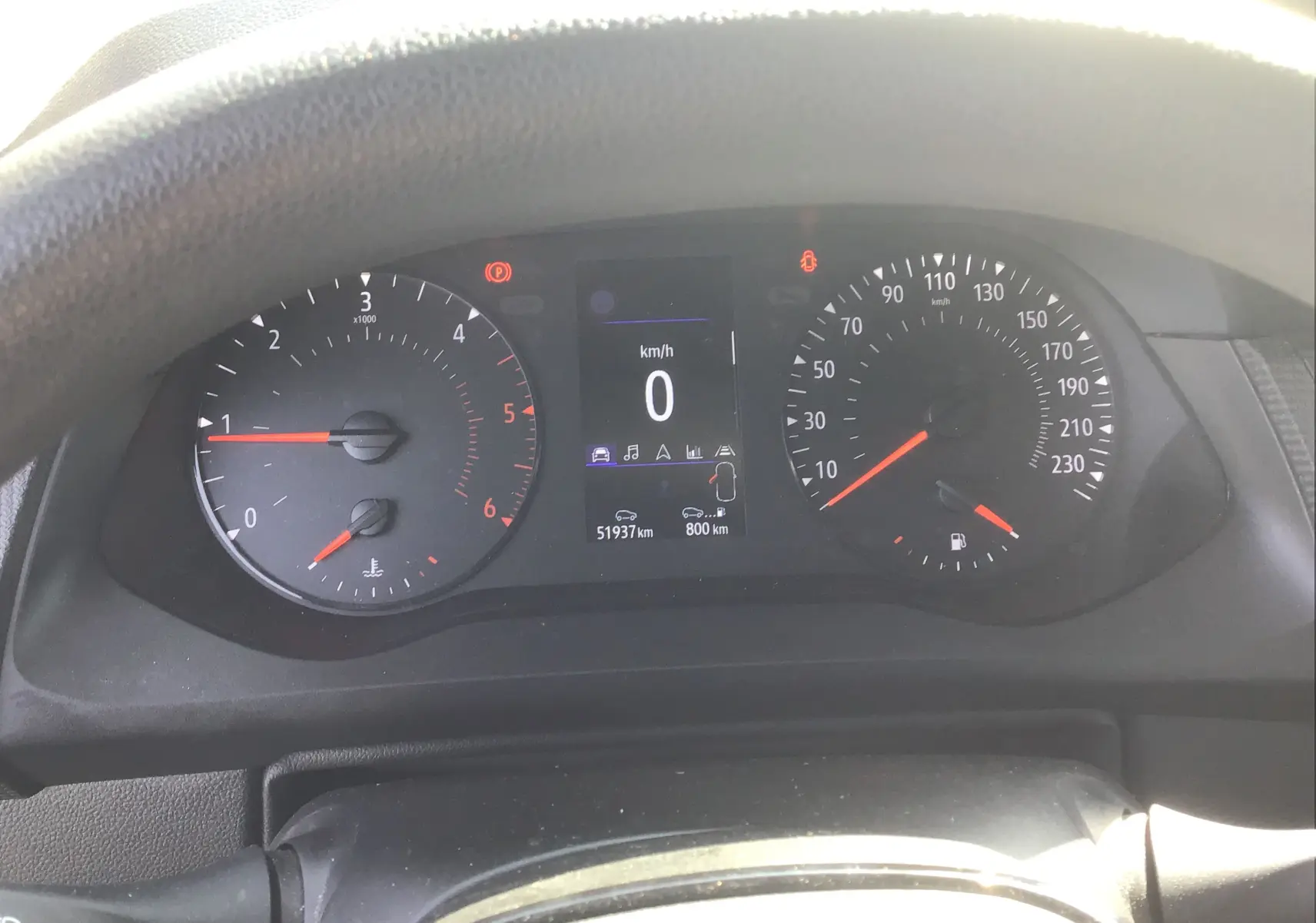 Tableau de bord du Renault Kangoo blanc 2024, affichage numérique au centre avec compte-tours et compteur vitesse analogiques.