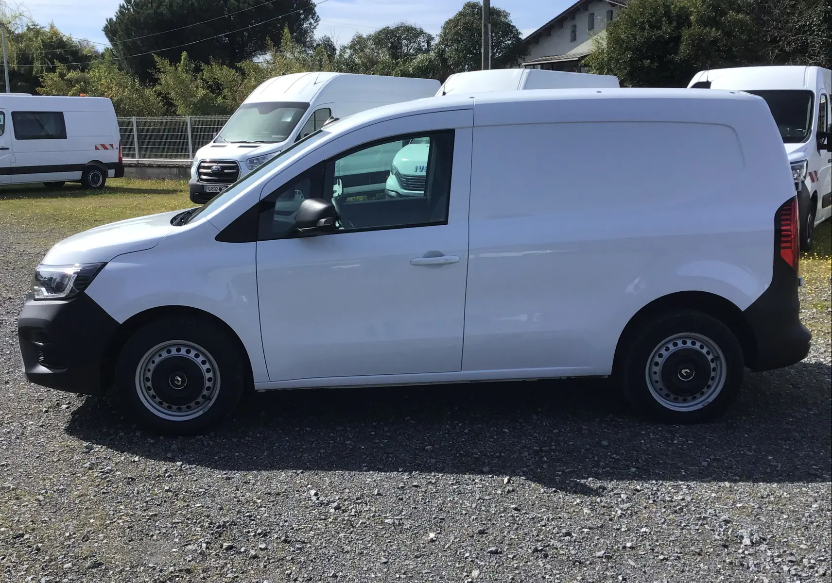Vue de profil côté gauche du Renault Kangoo Van blanc 2024 avec jantes acier et boucliers noirs contrastants.