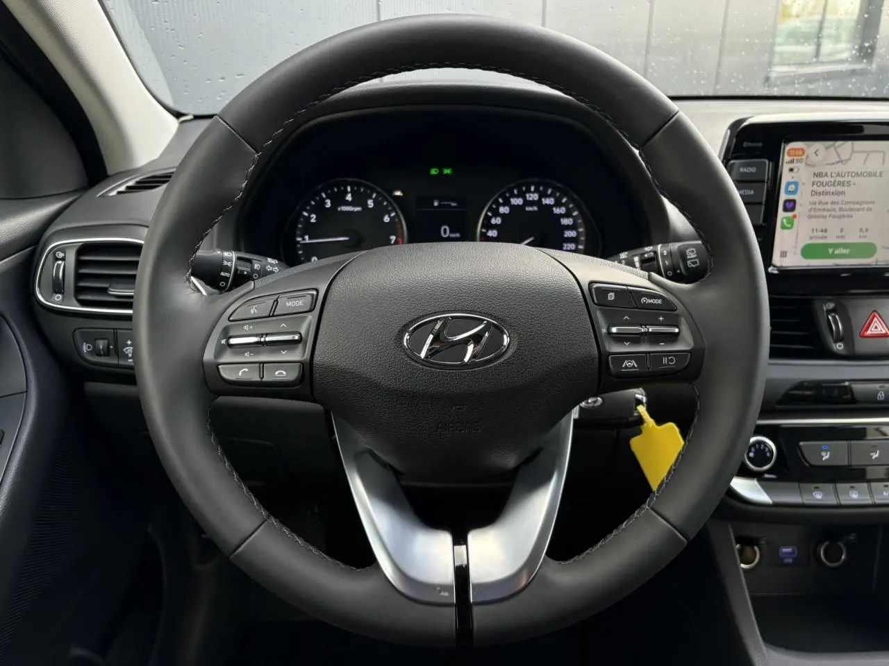 Vue intérieure centrée sur le volant cuir noir de la Hyundai i30 SW 2025 avec tableau de bord et écran tactile multimédia.
