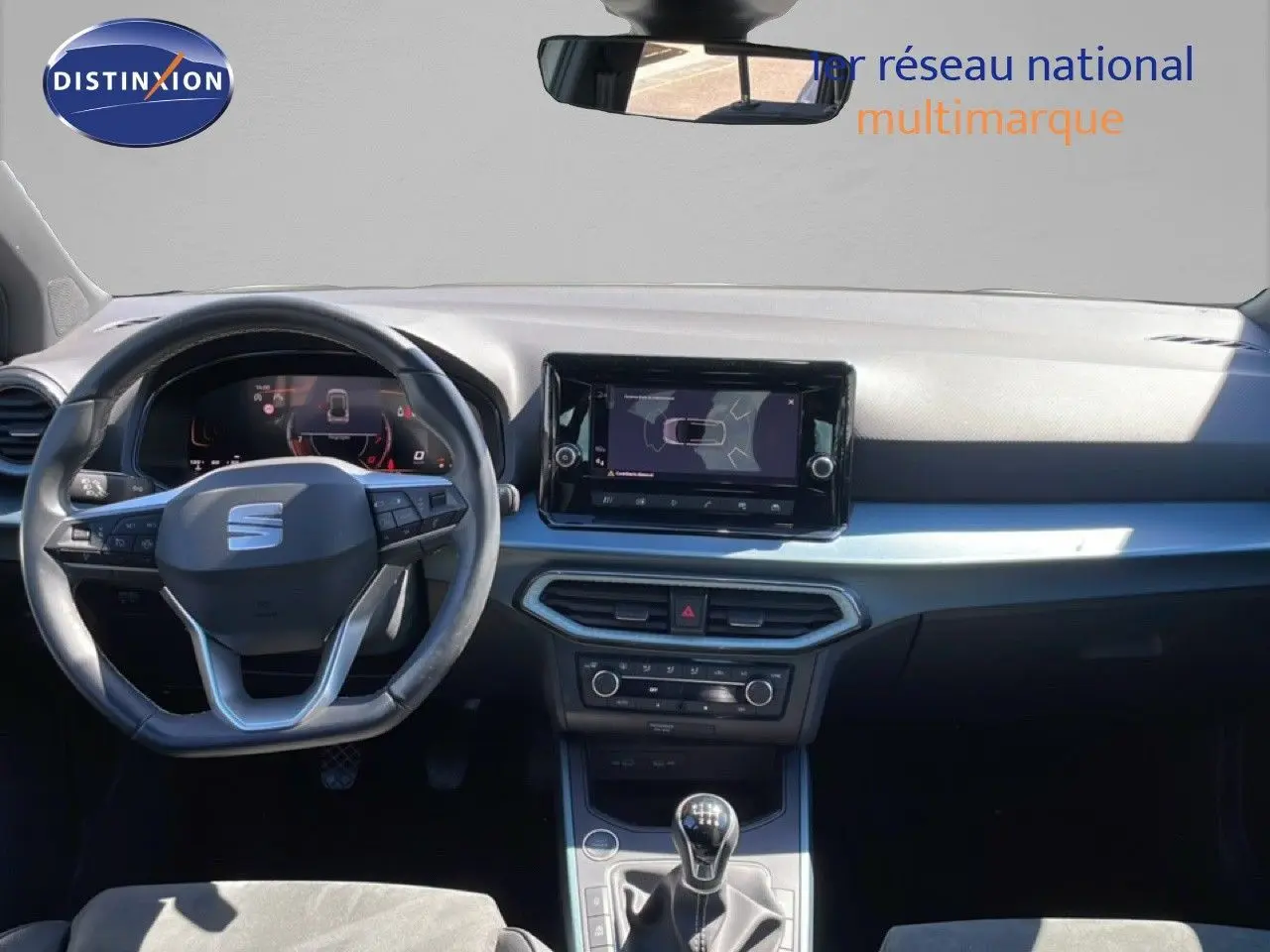 Vue intérieure frontale du tableau de bord du SEAT Arona blanc, avec volant cuir multifonction et écran tactile central.