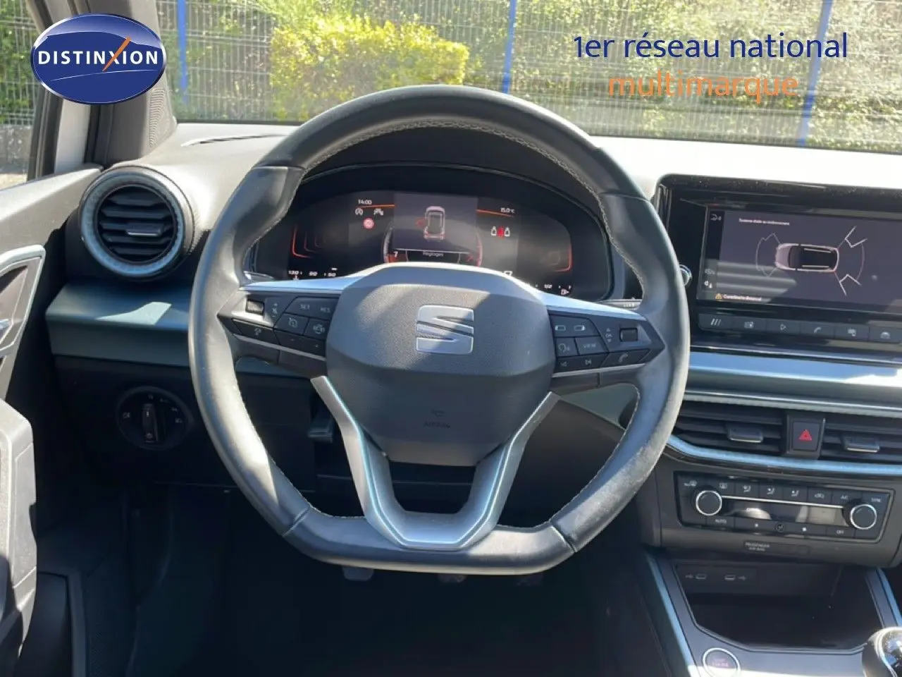 Vue intérieure centrée sur le volant cuir et le tableau de bord numérique du SEAT Arona 2025, ambiance noire moderne.