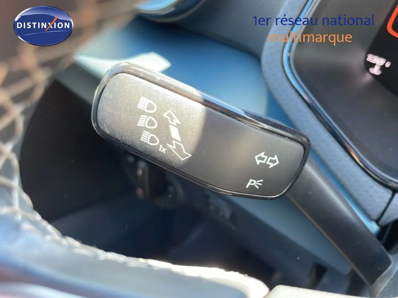 Gros plan sur la commande de clignotants et feux d’un SEAT Arona blanc toit noir, intérieur noir visible en arrière-plan.