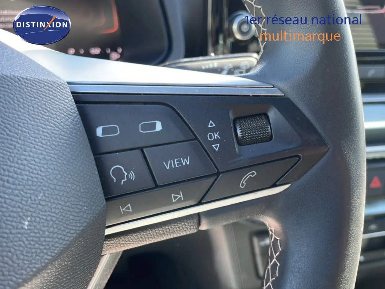 Gros plan sur les commandes multifonctions à droite du volant en cuir noir du SEAT Arona blanc toit noir, 2025.