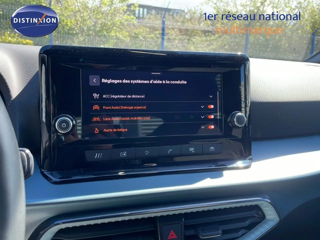 Vue intérieure centrée sur l'écran tactile du tableau de bord du SEAT Arona blanc toit noir, affichant les aides à la conduite.