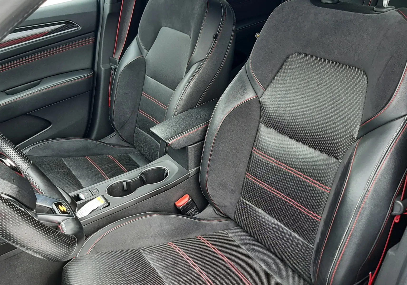 Vue intérieure rapprochée des sièges avant noirs avec surpiqûres rouges du Renault Arkana E-Tech 145ch RS-Line 2021.