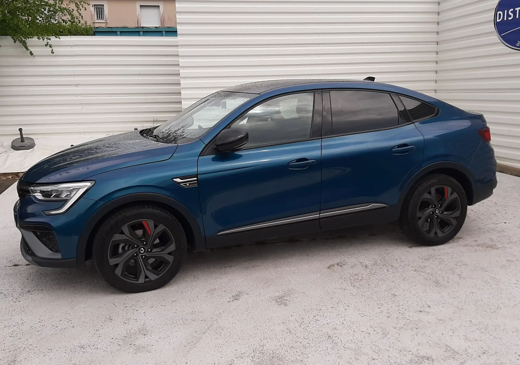Profil côté gauche du Renault Arkana E-TECH 145ch RS-Line bleu Zanzibar, avec jantes noires et détails sportifs rouges.