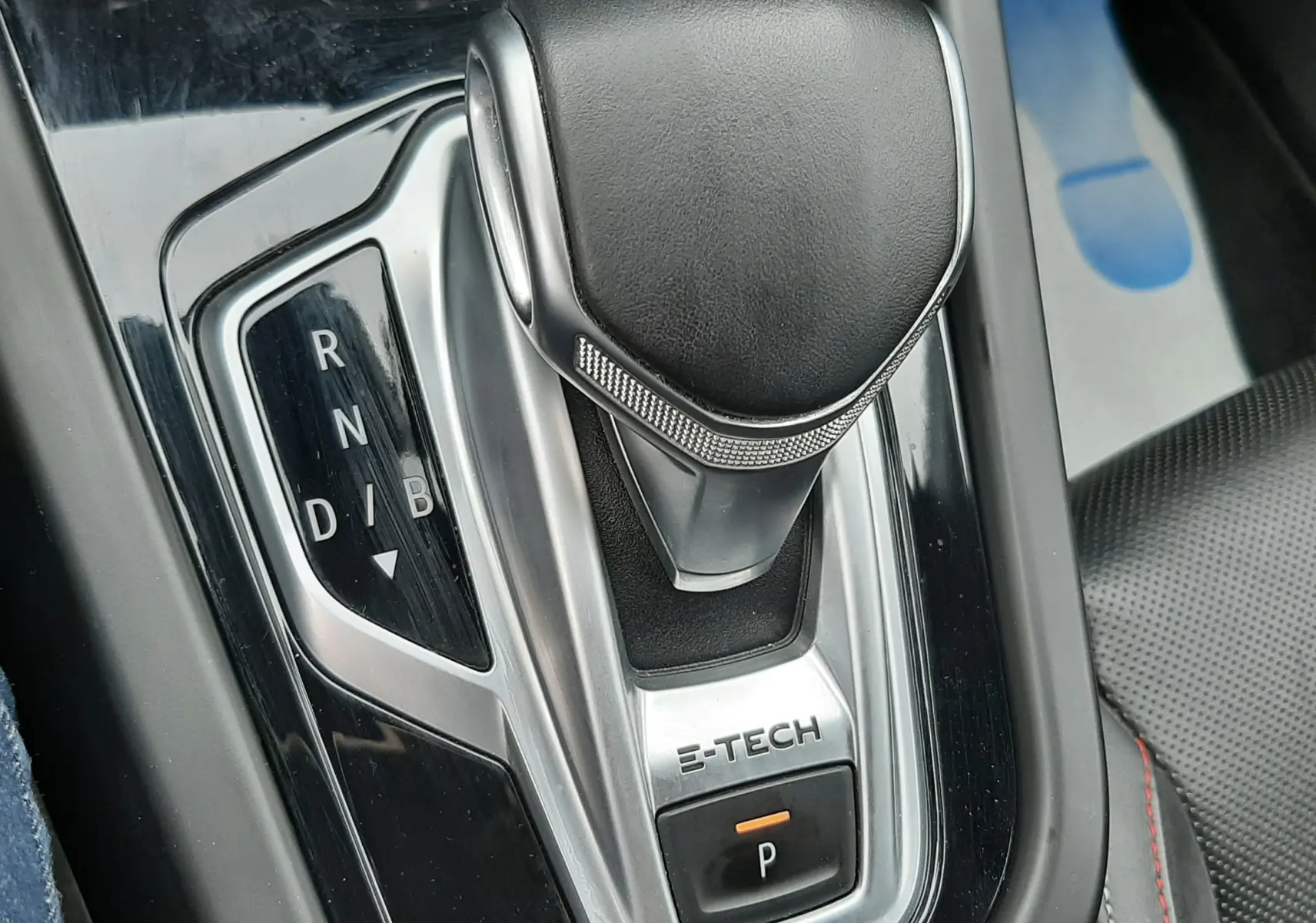 Gros plan sur la commande de boîte automatique E-TECH du Renault Arkana, avec levier en cuir noir et console brillante.