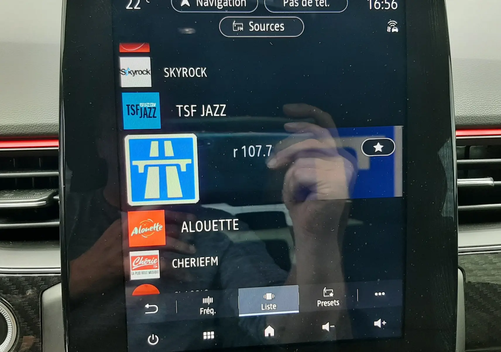 Écran tactile central du tableau de bord du Renault Arkana E-Tech bleu Zanzibar, affichant les stations radio et la navigation.