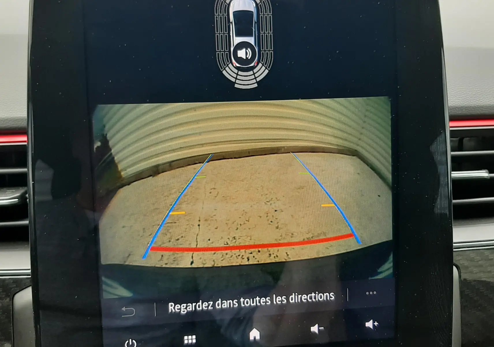 Écran central montrant la caméra de recul du Renault Arkana bleu Zanzibar avec lignes d’aide au stationnement.
