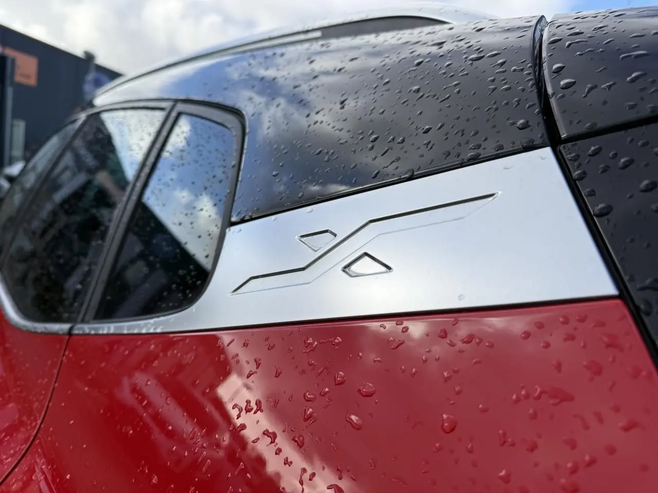 Détail du montant arrière droit rouge et noir du SEAT Arona 2024 avec insert décoratif argenté sous la pluie.