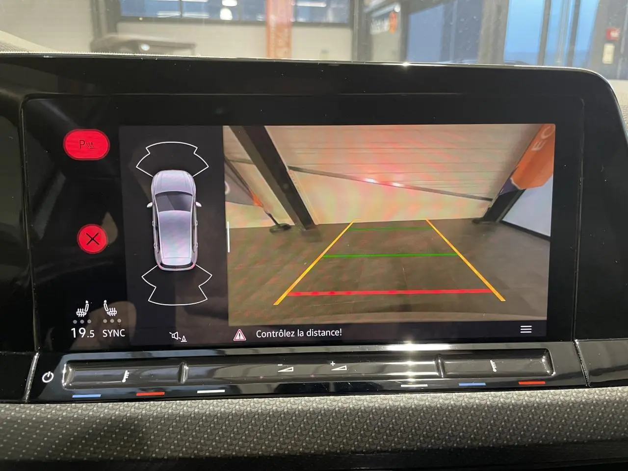 Écran de caméra de recul et capteurs de stationnement d’une Volkswagen Golf blanche vue de l’intérieur.