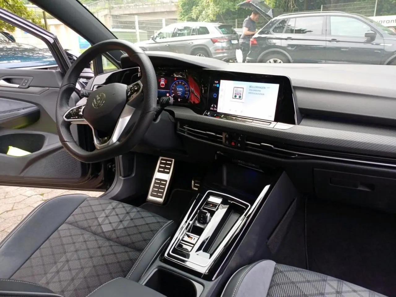 Vue intérieure côté conducteur de la Volkswagen Golf blanche 2024, avec tableau de bord digital et volant multifonctions cuir.