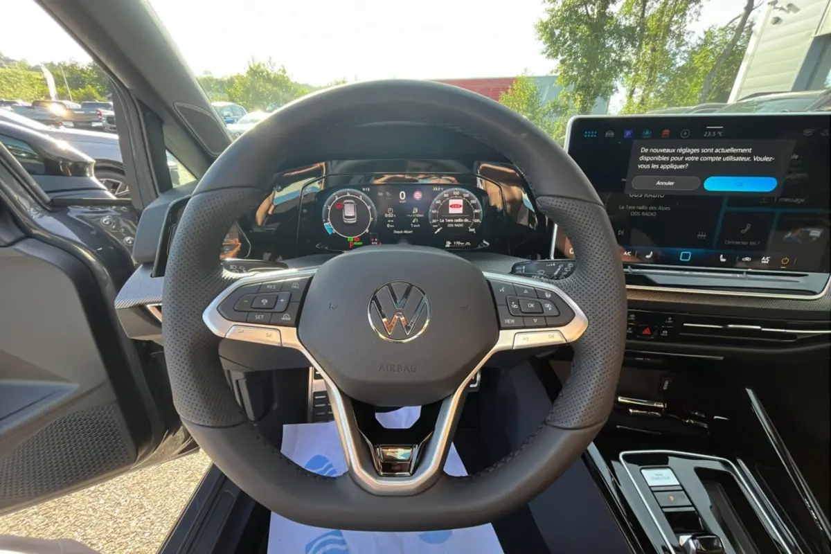 Vue intérieure centrée sur le volant cuir multifonctions d'une Volkswagen Golf gris dauphin avec tableau de bord numérique.