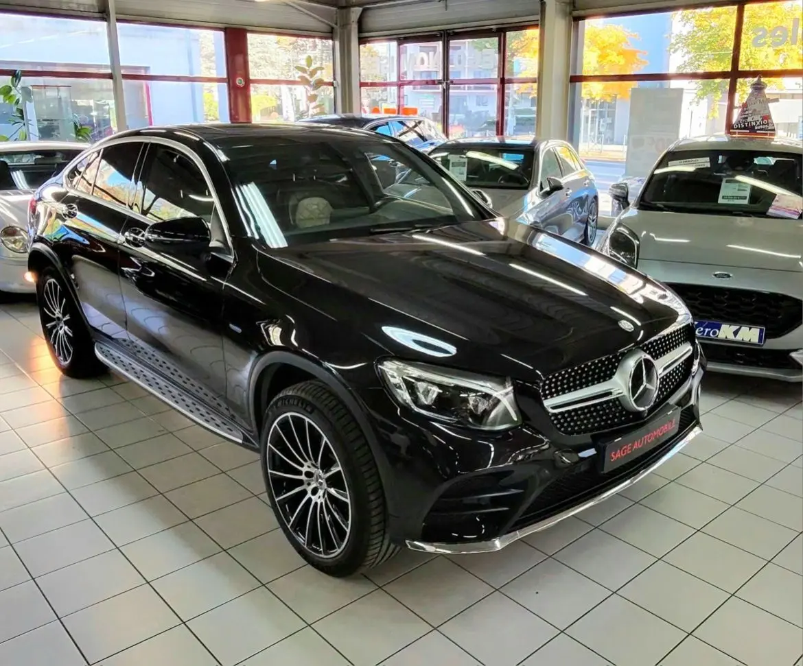 Vue 3/4 avant d'une Mercedes GLC Coupé noire brillante avec jantes sport bicolores en concession.