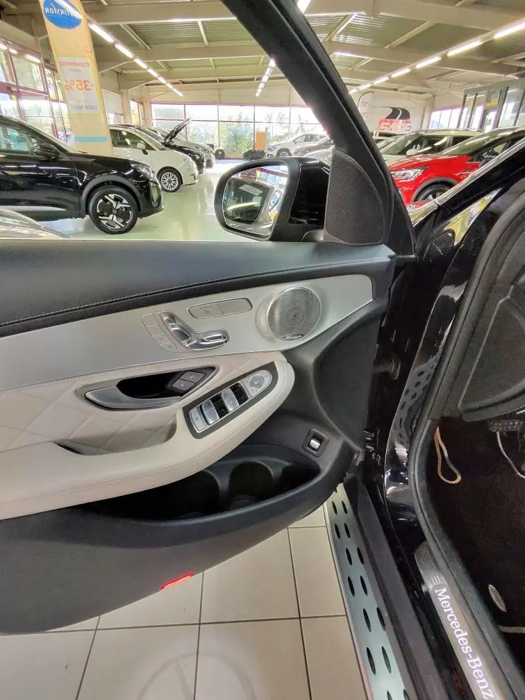 Vue intérieure côté gauche de la porte avant d’une Mercedes GLC 350 noire, mettant en valeur les commandes et la finition cuir claire.