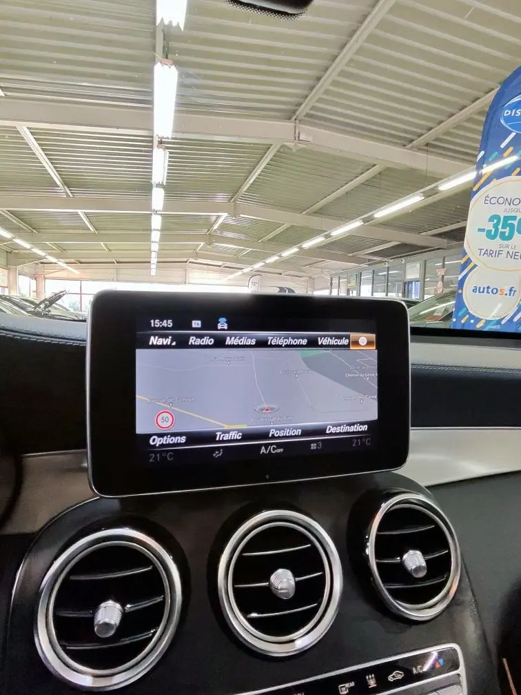 Vue rapprochée de l’écran central multimédia et des aérateurs ronds chromés de la Mercedes GLC 350 Coupé noire.