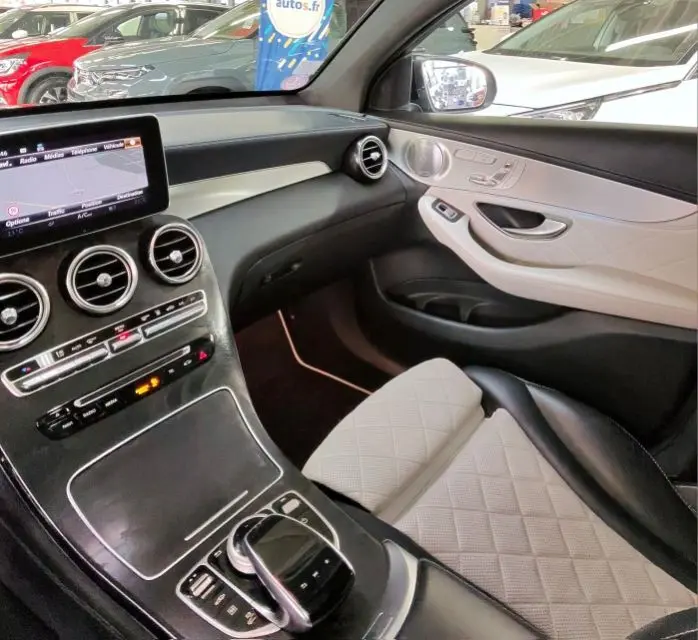 Intérieur de la Mercedes GLC 350 Sportline 2017, vue côté passager, sièges cuir blanc et tableau de bord noir avec écran central.