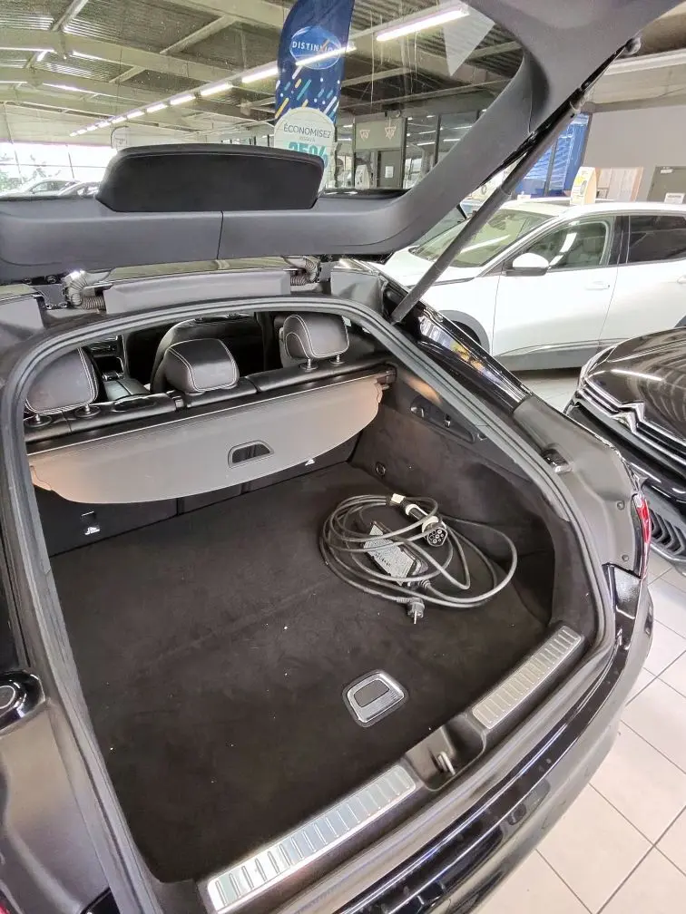 Coffre ouvert vu de l'arrière d'une Mercedes GLC Coupé noire, avec câble de recharge hybride visible à l'intérieur.