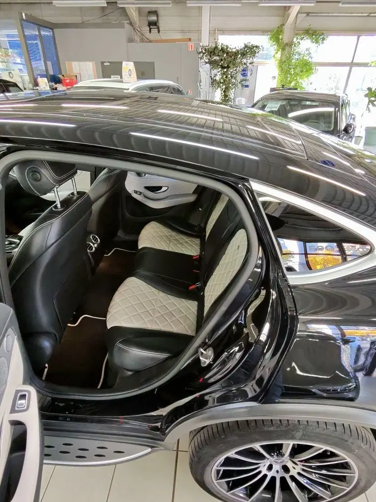 Vue côté arrière gauche du Mercedes GLC Coupé noir, mettant en valeur l'intérieur cuir bicolore et les sièges arrière élégants.