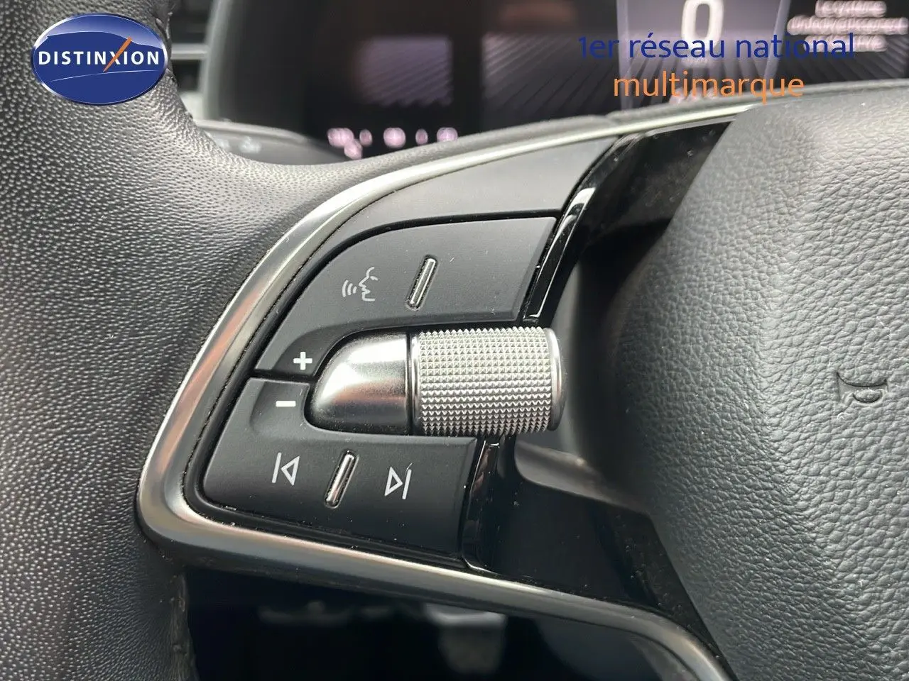 Gros plan sur les commandes multimédia au volant en cuir noir d'une Skoda Kamiq rouge Velvet Metal 2024.